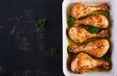Baked chicken drumsticks on a dark background. Top view, flat lay