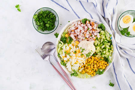 Festive salad with ham, cucumber, boiled eggs, sweet corn and mayonnaise on rustic. Top view, aboveの写真素材