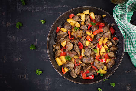 Fried chicken liver with apples and sweet peppers in iron skillet. Top view, flat layの写真素材