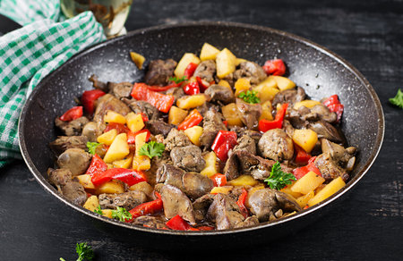 Fried chicken liver with apples and sweet peppers in iron skillet.の写真素材