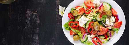 Greek salad of fresh tomato, sweet pepper, cucumber, red onion, feta cheese and green olives. Healthy vegetarian food. Top view, bannerの写真素材