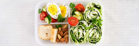 School lunchbox. Healthy lunch box with tortilla wraps with cream cheese, cucumber and letucce. Nuts and vegetable. Top view, bannerの写真素材