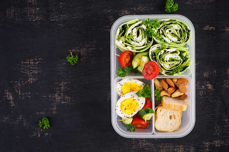 School lunchbox. Healthy lunch box with tortilla wraps with cream cheese, cucumber and letucce. Nuts and vegetable. Top view, flat layの写真素材