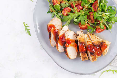 Roasted chicken fillet with salad fresh tomatoes and arugula. Top view, flat layの写真素材