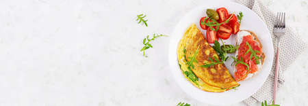 Breakfast. Omelette with cheese, green arugula and sandwich with salmon on white plate. Frittata - italian omelet. Top view, bannerの写真素材