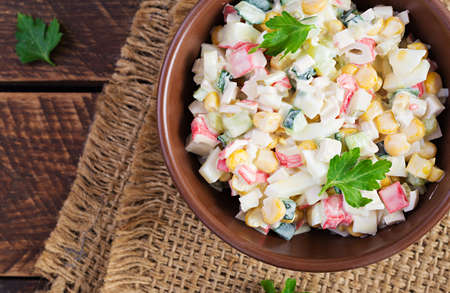 Salad with corn and crab sticks in bowl on wooden table. Traditional Russian cuisine.Top view, overheadの写真素材