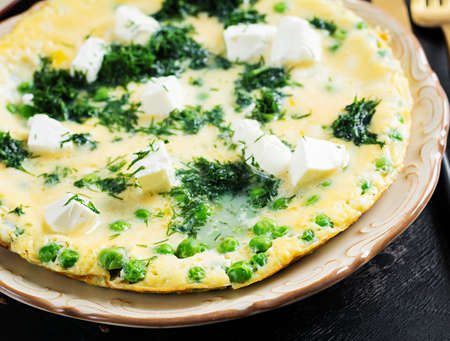 Healthy breakfast. Omelet with green peas, feta cheese and dill. dark background.の写真素材