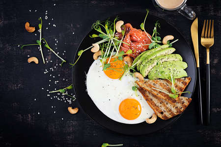 Ketogenic diet breakfast. Fried eggs, salt salmon with microgreens, avocado, cashew nuts and keto...