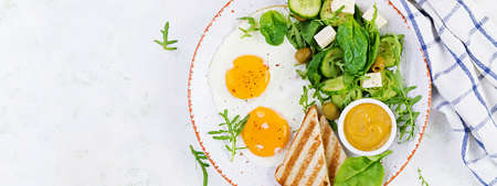 English breakfast - fried eggs, cheese, cucumber, olives and spinach. american food. top view, overhead, bannerの写真素材