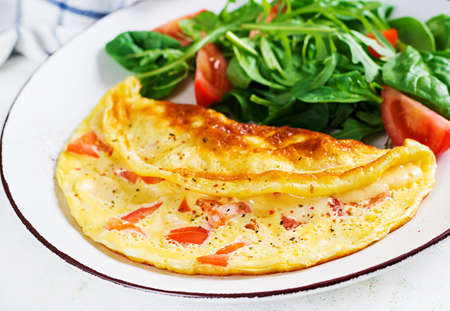 Omelette with tomatoes and salad on white plate. Frittata - italian omelet.の写真素材