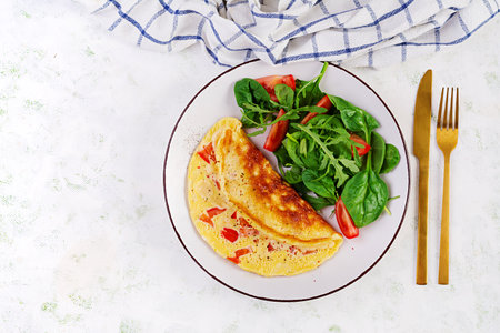 Omelette with tomatoes and salad on white plate. Frittata - italian omelet. top view