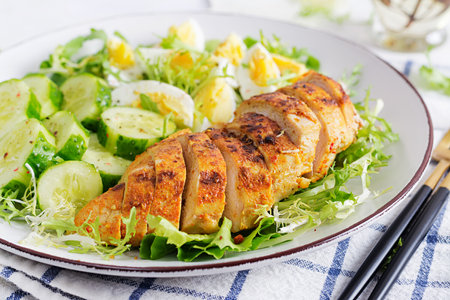 Grilled chicken meat and boiled eggs and fresh cucumber salad. Healthy keto, ketogenic lunch. Roasted chicken breast, fillet and fresh vegetable salad.の写真素材