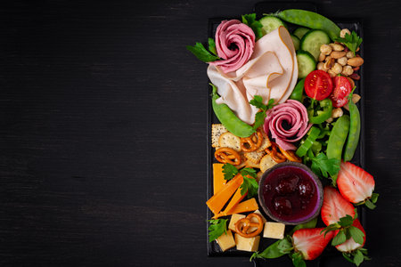 Antipasto platter cold sliced ham, salami, crackers, strawberries, vegetables and cheese platter on...