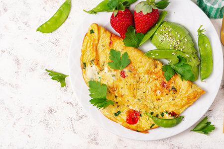 Omelette with tomatoes, feta cheese and avocado on white plate. Top view, flat lay