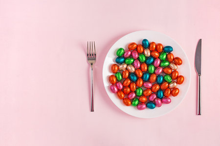 Happy Easter. Table setting for Easter holiday. Easter chocolate eggs and cutlery on pink background. Top view, flat layの写真素材