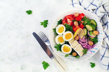 Breakfast. Greek salad and boiled eggs. Fresh vegetable salad with tomato, cucumbers, olives, arugula and cheese. Trendy food. Top view, flat layの写真素材
