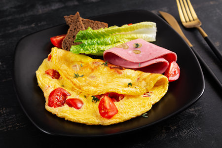 Omelette with tomatoes and cheese with bread and mortadella sausage.の写真素材