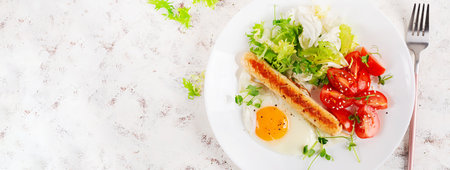 Keto breakfast. Fried egg and chicken sausage and fresh salad. Top view, bannerの写真素材