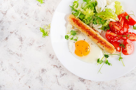 Keto breakfast. Fried egg and chicken sausage and fresh salad. Top view, flat layの写真素材