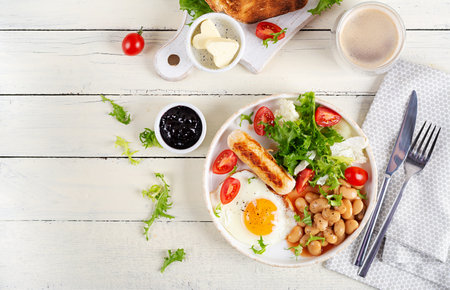 English breakfast. Keto breakfast. Fried egg, beans, chicken sausage and coffee cup. Top view, flat...