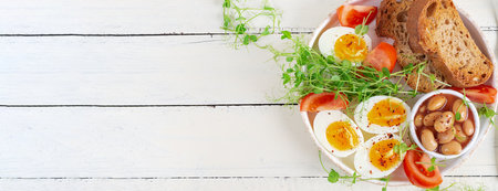 English breakfast. Boiled eggs, beans, toast and green herbs. Top view, banner