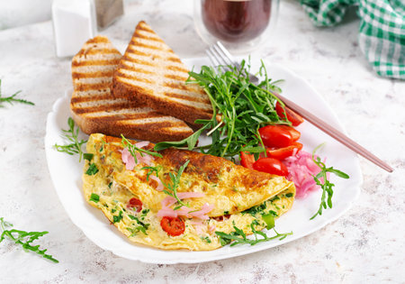 Healthy breakfast. Omelette with cheese, tomatoes and green herbs. Omelette, salad and toast. Keto, ketogenic lunch.の写真素材