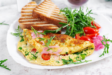 Healthy breakfast. Omelette with cheese, tomatoes and green herbs. Omelette, salad and toast. Keto, ketogenic lunch.の写真素材