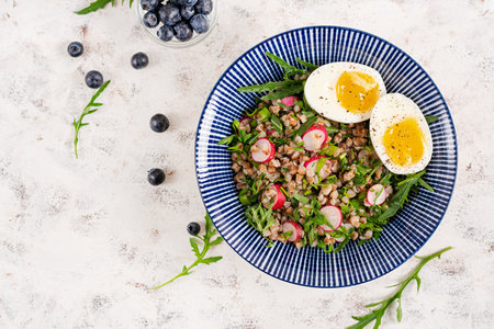 Healthy breakfast. Buckwheat porridge with boiled egg, radish and green herbs. Buckwheat tabbouleh. Top viewの写真素材
