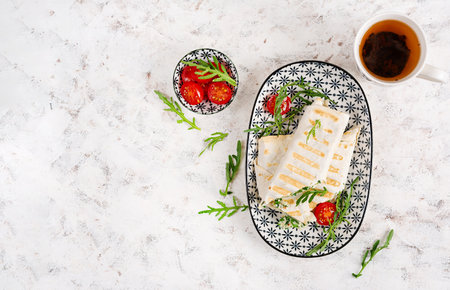 Tasty breakfast with lavash. Mexican cuisine Trending food with pita bread, cheese, tomatoes and spinach. Top viewの写真素材