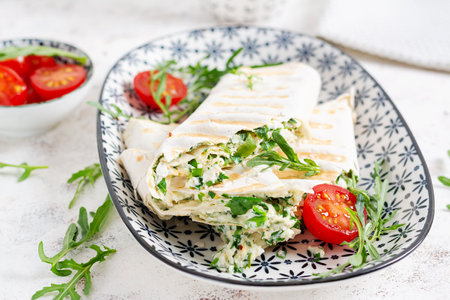 Tasty breakfast with lavash. Mexican cuisine Trending food with pita bread, cheese, tomatoes and spinach.の写真素材