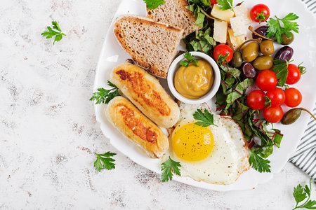 Fried egg, homemade chicken sausage, toasts and fresh salad. Keto, paleo breakfast. Top view, flat layの写真素材
