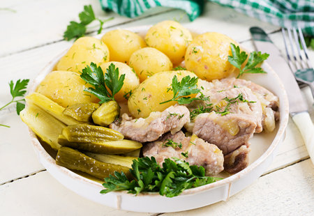Boiled new potatoes with pieces of stewed pork and pickled cucumbers. Simple food. Country food. Tasty food. Lunchの写真素材