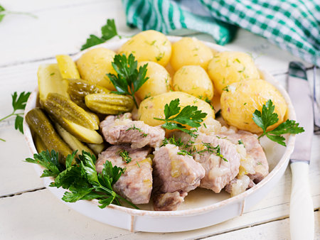 Boiled new potatoes with pieces of stewed pork and pickled cucumbers. Simple food. Country food. Tasty food. Lunchの写真素材