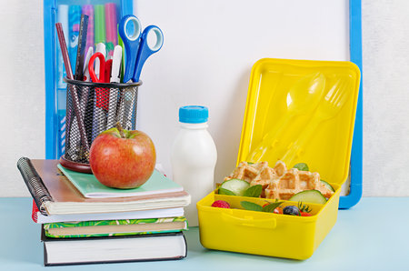 Kids lunch box with zucchini waffles, cucumber, cherry tomatoes and blueberries. Back to school breakfast background. Copy space. Top view, flat layの写真素材