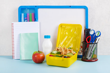 Kids lunch box with zucchini waffles, cucumber, cherry tomatoes and blueberries. Back to school breakfast background. Copy space. Top view, flat layの写真素材