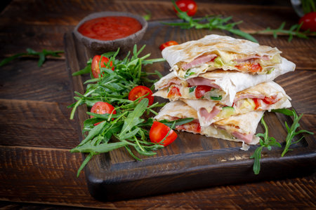 Traditional Mexican quesadillas with sliced ham also called sincronizadas on wooden background....