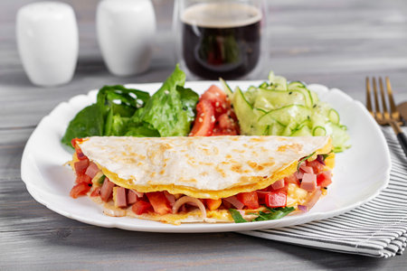 Healthy breakfast. Quesadilla with omelet, ham, cheese, and tomatoes.