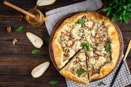 Baked galette or open pie with pear, blue cheese and nuts on the wooden table. Top viewの写真素材