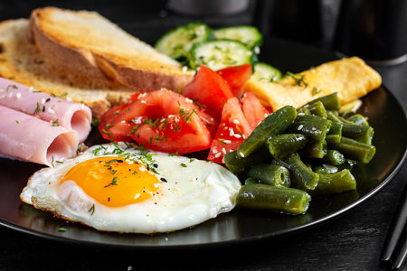 English breakfast - fried egg, ham, green beans, tomatoes, cucumbers and toast.の写真素材