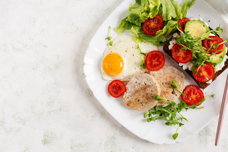 Fried egg, chicken and sandwich with tomatoes, avocado and cheese. Top viewの写真素材