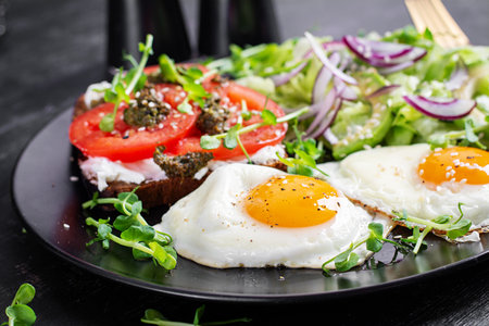 Fried egg, fresh salad and sandwich with tomatoes, pesto and cream cheese.の写真素材