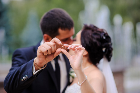 bride and groom holding the ring in the foregroundの写真素材