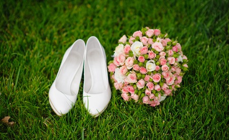 wedding bouquet and shoes lying down on green grassの写真素材