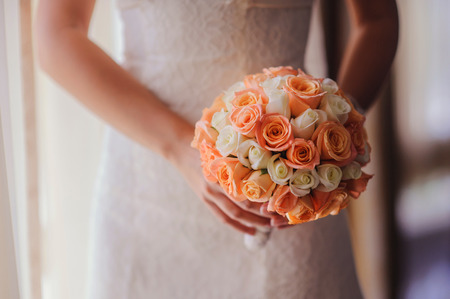 bride holding a wedding bouquet with white and pink rosesの写真素材