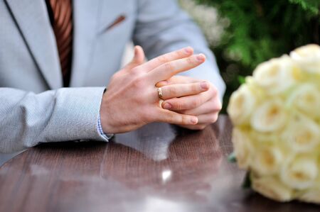 Groom is sitting at the table and twists the ring on her fingerの写真素材