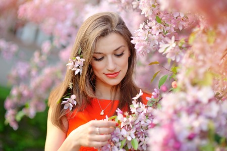 beautiful young brunette woman standing near the apple tree.の写真素材