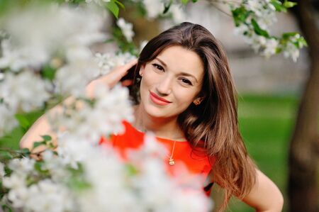 Portrait of pretty girl near the blossomed tree in the park. Concept of youth and natural beautyの写真素材