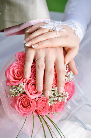 hand the bride and groom with the rings lying on the bridal bouquet.の写真素材
