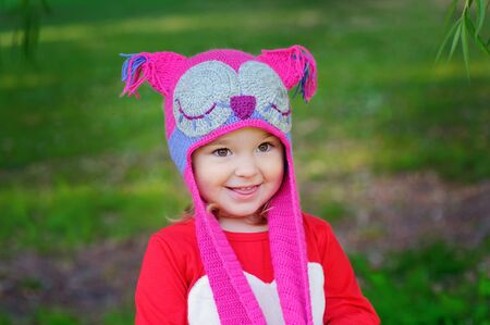 Cute little girl on the meadow in summer day a knitted hat owlの写真素材