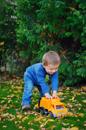 joyful baby boy in autumn park playing machine.の写真素材